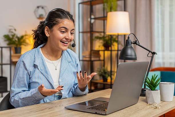 istock Young female customer service representative with headset using laptop computer at home office table 2218683008