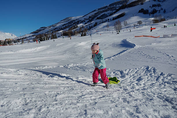 istock Child joyfully drags sled across sparkling under clear blue sky 2218683960