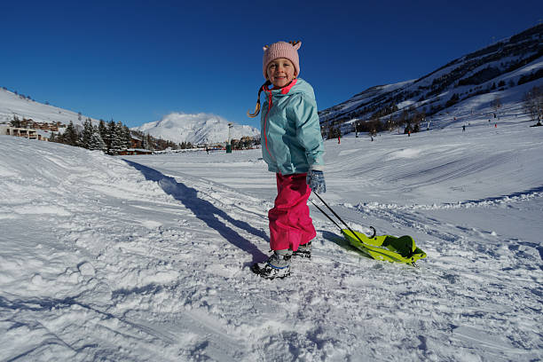 istock Child in winter gear pulling sled on snowy mountain hill trail 2218683965