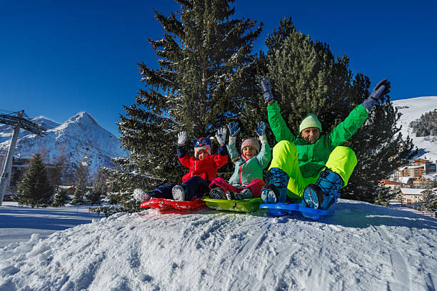 istock Siblings sit together on sled at sunlit slope with distant peaks 2218684521