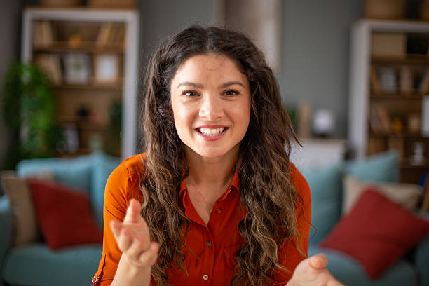 Cheerful young woman having a video call, talking and smiling at home