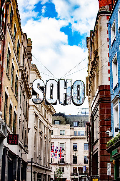 Urban view of Soho in London featuring a prominent sign and Union Jacks in the background.