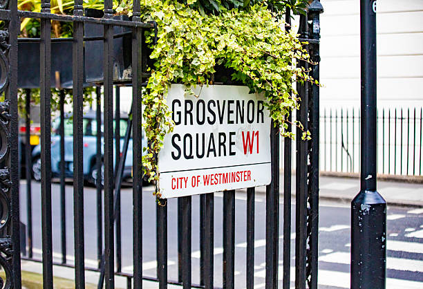 Street sign for Grosvenor Square in the City of Westminster, London. The image shows a classic urban setting with greenery.