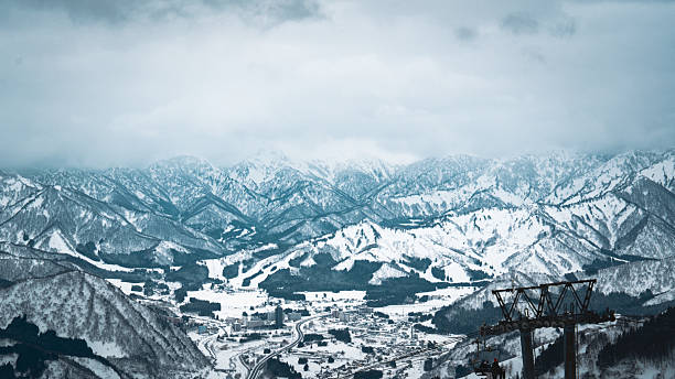 A breathtaking panoramic view of snow-covered mountain ranges including Ishiuchi Maruyama, Yuzawa Kogen, and distant peaks near Echigo-Yuzawa in Niigata, Japan, captured from Gala Yuzawa station.