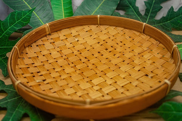 istock A versatile round woven bamboo tray, showcasing its natural texture and artisanal craftsmanship, framed by vibrant green leaves, ideal for organic product presentation or rustic home decor 2218694305