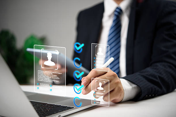 istock Businessman using digital interface to select candidates with virtual profile icons and checkmarks, representing modern recruitment, HR human resources technology, and hiring process. 2218704266