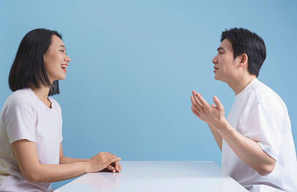 istock Two Friends Engaged in Conversation at a Table Against a Blue Background 2218710167