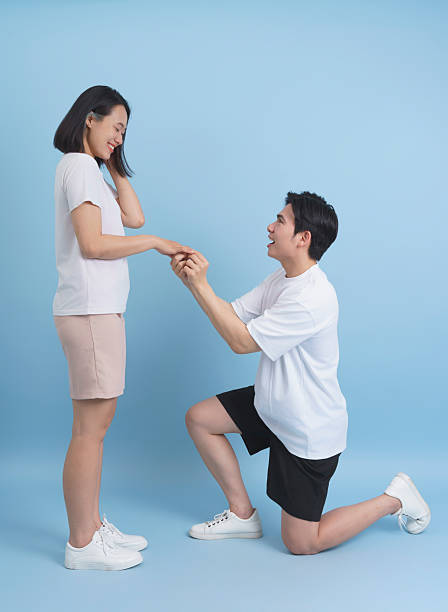 istock Man Proposing with Engagement Ring to Smiling Woman on Blue Background 2218710186