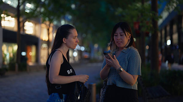 istock Female solo traveler using artificial intelligent mobile app to communicate and ask directions to local person in city street in Tokyo 2218715921