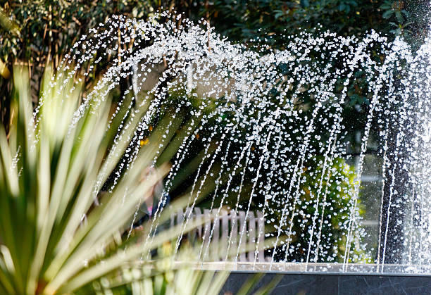 A fountain with a person in the background. The water is white and is spraying out of the fountain