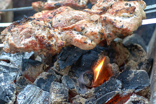 Cooking kebabs on a grill with smoke. Fresh brown BBQ meat cooked on an outdoor grill.