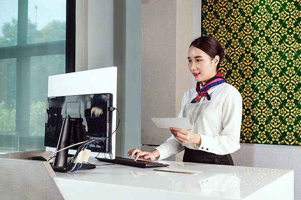 istock Airline ground staff in uniform processes a boarding pass at a modern check-in counter. Captures professionalism, customer service, and travel efficiency in an airport setting. 2218719258