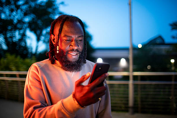 istock Man illuminated by a smartphone in a city at night 2218719471