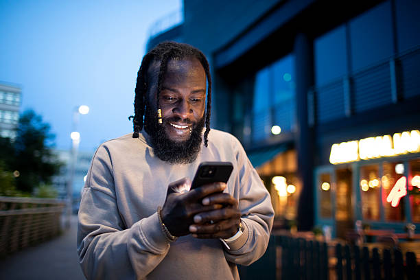 istock Man using a smartphone outside an illuminated city restaurant at night 2218719482
