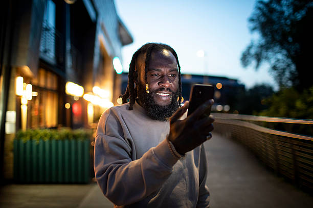 istock Man using a smartphone outside illuminated city buildings at night 2218719521