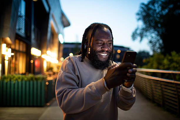 istock Cheerful man using a smartphone outside illuminated city buildings at night 2218719591