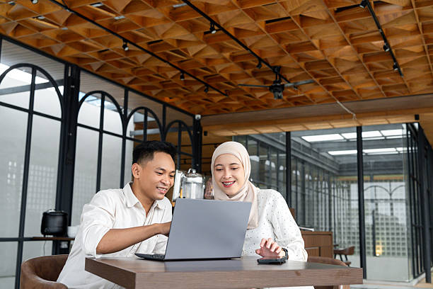istock Smiling Colleagues Collaborating on a Laptop in a Modern Workspace. Two professionals working together on a laptop in a contemporary office setting, demonstrating teamwork and productivity 2218720830