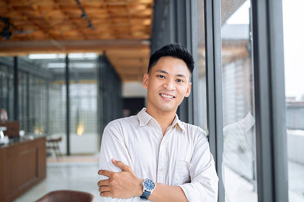 istock Cheerful young professional stands confidently in a modern, well-lit office space, exuding positivity and success. Perfect for business or work environments concept. 2218721177
