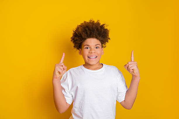 istock Smiling young boy with a curious gesture on a vibrant yellow background expressing joy and energy 2218722739