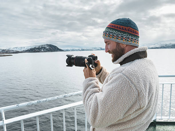 istock Man Capturing Scenic Winter Landscape on Ferry Deck 2218722919