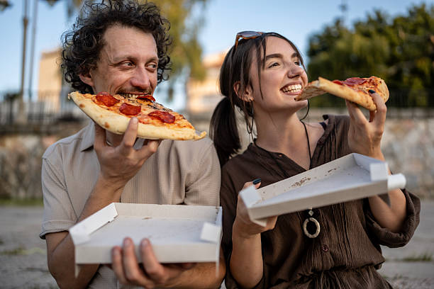 istock Two Friends Enjoying Pizza Outdoors in a Relaxing Urban Park Setting 2218724702