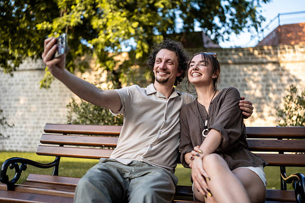 istock Happy Couple Taking a Selfie on a Park Bench in Summer 2218725318