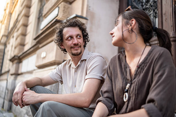 istock Friendly Conversation Between Two People Sitting Outdoors on an Urban Street 2218725404