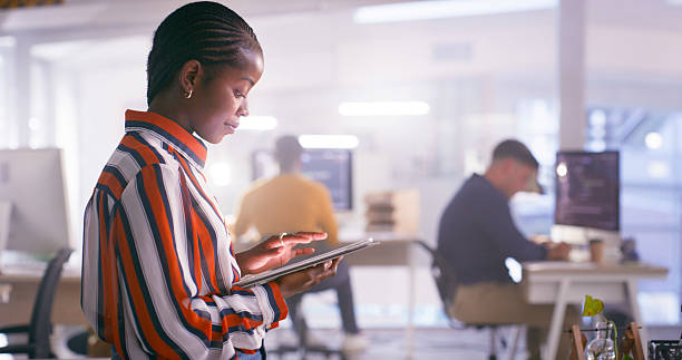 istock Focused Professional Woman Using a Digital Tablet in a Modern Open Office Setting 2218728015