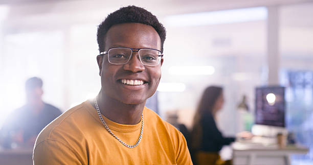 istock Smiling Young Professional in a Modern Office Environment with Creative Colleagues in Background 2218728061