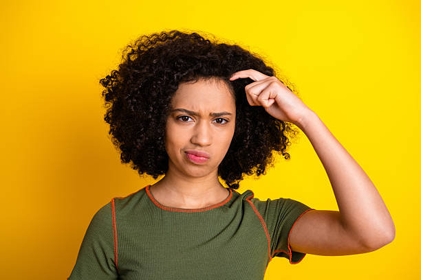 istock Young woman making gestures with a thoughtful expression against a vibrant yellow background wearing a stylish outfit 2218732171