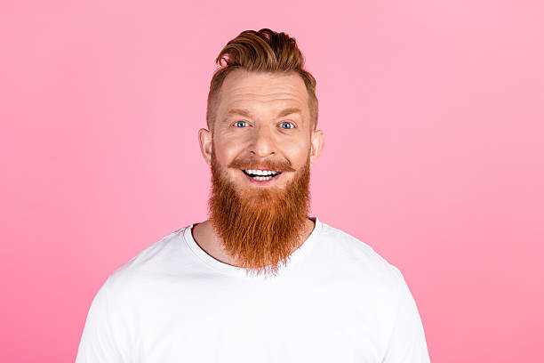 istock Cheerful red haired man posing against a pink background, showcasing a stylish look and friendly smile in casual fashion 2218735112