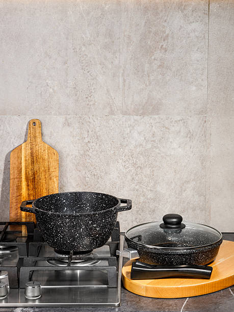 istock Two black pots sit on a stove next to a wooden cutting board 2218738059