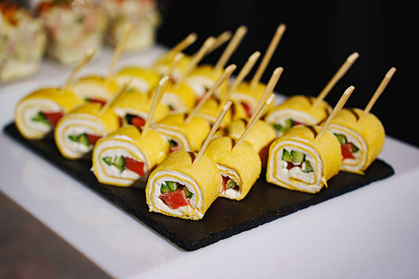 Colorful sushi rolls displayed on a black platter at a catering event