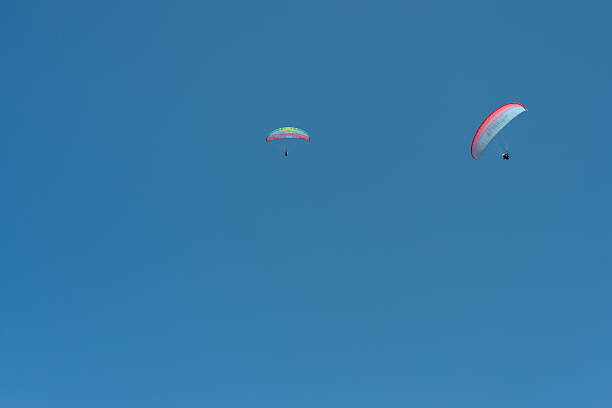 istock Two paragliders soaring in a clear blue sky on a sunny day 2218743612