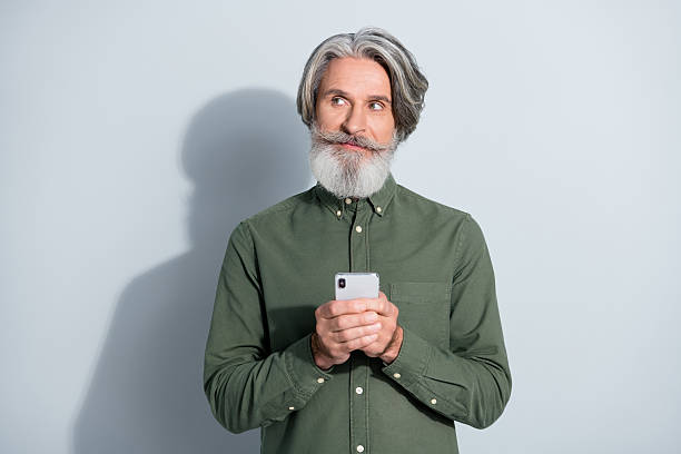 istock Portrait of attractive minded grey-haired man using device chatting creating post smm isolated over gray pastel color background 2218748836