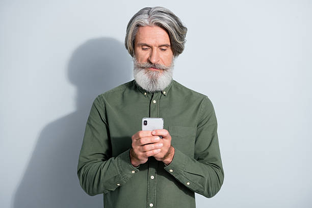 istock Portrait of attractive focused grey-haired man using gadget chatting browsing media post smm isolated over gray pastel color background 2218748837