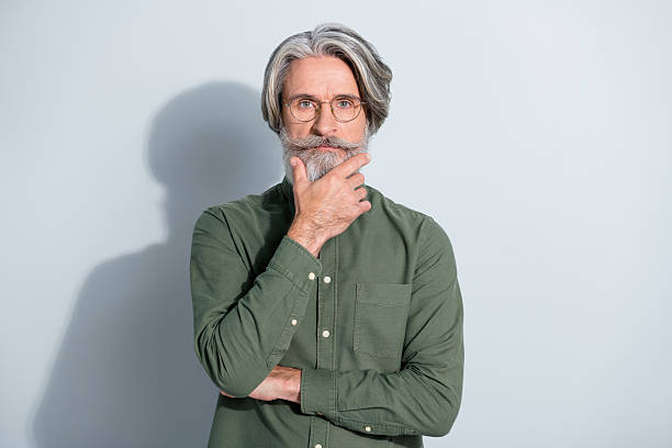 istock Portrait of attractive focused grey-haired man professor touching beard thinking isolated over gray pastel color background 2218749352