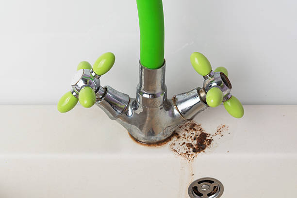 istock Old water faucet with bright green handles and visible rust stains on sink base reflects need for plumbing maintenance and timely repairs. 2218754098