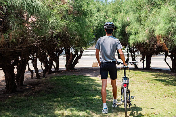 Young cyclists man walking on public park