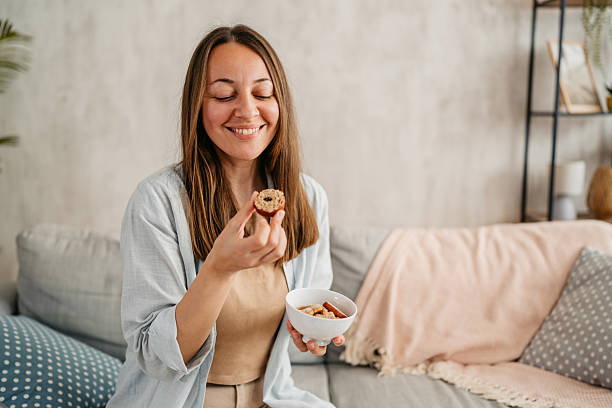 istock Young Woman Eating Cookies While Sitting On The Sofa 2218755416