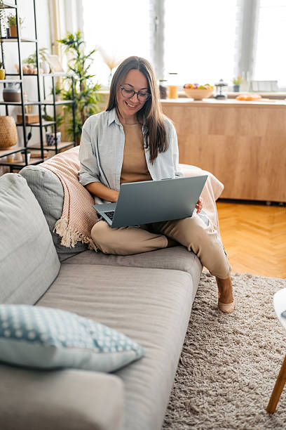 istock Young Woman Working On A Laptop While Sitting On The Sofa At Home 2218755792