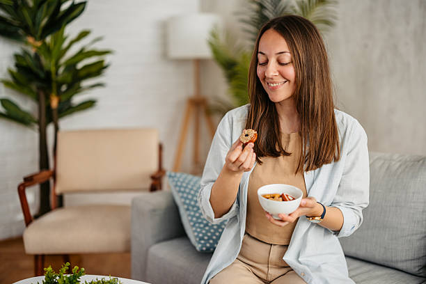 istock Young Woman Eating Cookies While Sitting On The Sofa 2218756780