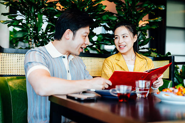 istock Young Asian couple reading the menu in restaurant.  chatting joyfully and having drinks after work. Dining out. People, lifestyle, food and drink concept. 2218759936