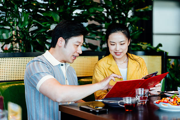istock Young Asian couple reading the menu in restaurant.  chatting joyfully and having drinks after work. Dining out. People, lifestyle, food and drink concept. 2218759940