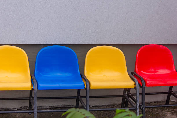multi-colored chairs, yellow, red, blue chair, bench, strength, against a gray wall