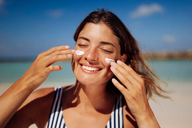 istock Smiling Woman Applying Sun Cream on Beach 2218762128