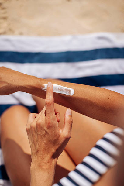 aplicar protector solar en una playa soleada - crema solar fotografías e imágenes de stock
