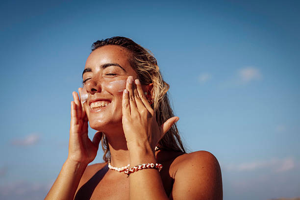 istock Smiling Woman Applying Sun Cream on Beach 2218762720