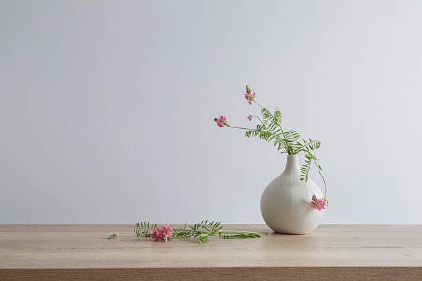 istock pink wild flowers in round ceramic vase on light wooden table 2218763503