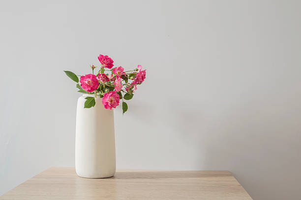 istock pink roses in ceramic vase on wooden table  in white interior 2218763525